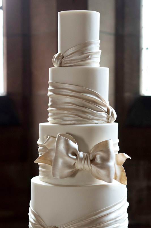 Six tier wedding cake with satin look sugar bow at Peckforton Castle in Cheshire